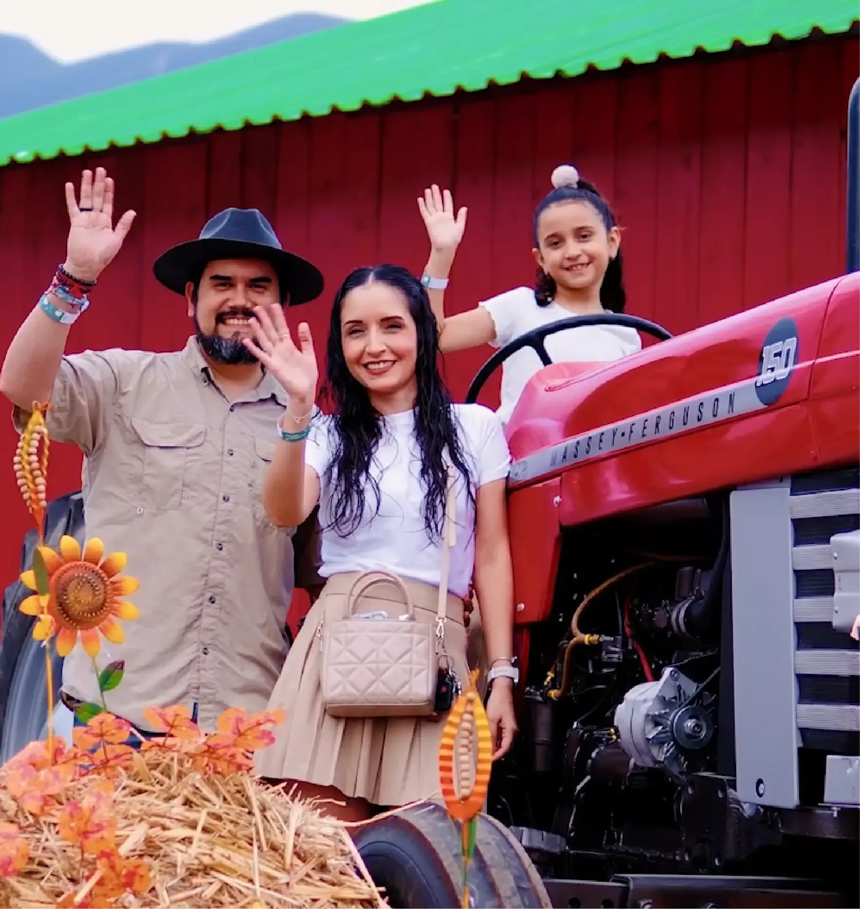 Familia saluda desde un tractor rojo